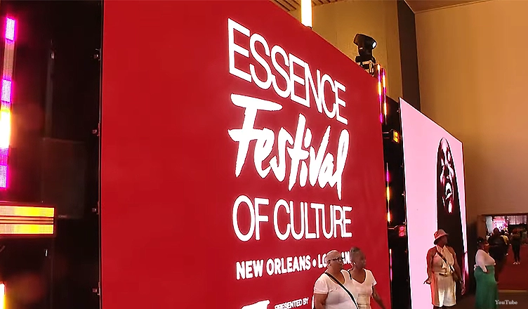 Essence Festival 2025 attendees take pictures in front of a sign. (Credit: YouTube/WWL)