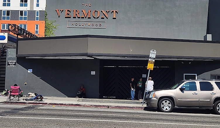 People stand outside The Vermont Hollywood while homeless individuals are seated nearby, Los Angeles, Sunday, July 20, 2025. (Credit: Urban Hollywood 411)