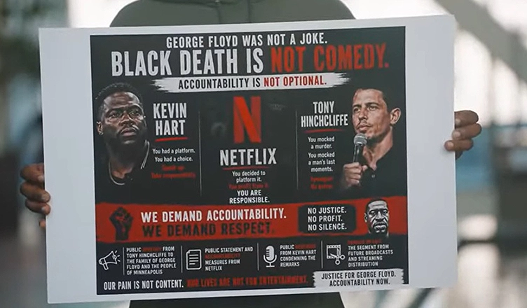 A protester holds a sign denouncing The Roast of Kevin Hart. (Credit: Screengrab)