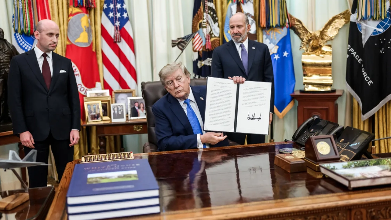 President Trump holds up a newly signed executive order in the Oval Office, alongside deputy chief of staff Stephen Miller, left, and Commerce Secretary Howard Lutnick, on Aug. 6, 2026. (Credit: WhiteHouse.Gov)